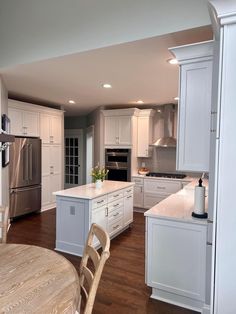 a large kitchen with white cabinets and wooden flooring, along with stainless steel appliances