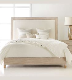 a bed with white linens and pillows in a clean bedroom setting on a white floor