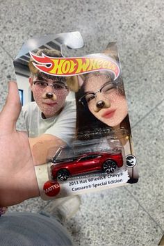 a hand holding a red hot wheels die cast car