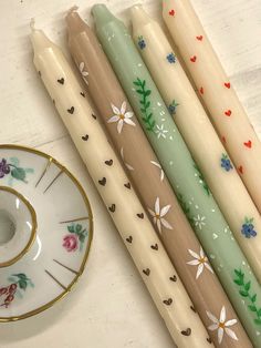 four candles sitting next to each other on top of a white table with a saucer