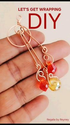 a hand holding a pair of earrings that have been made with wire and glass beads