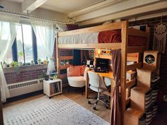 a loft bed with desk and chairs in a room next to a large window that has lots of windows