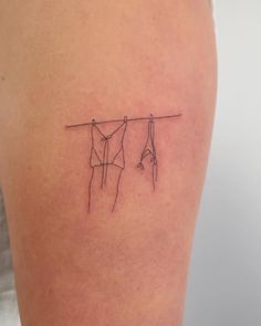 a woman's thigh with two clothes hanging on a line tattoo design by hand