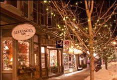 christmas lights adorn the storefronts and trees on a snowy street