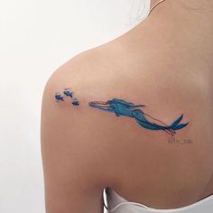 the back of a woman's shoulder with a blue bird tattoo on her left arm