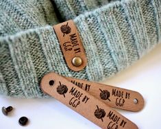 two knitting needles are next to a green knitted sweater with the name made by yarn written on it