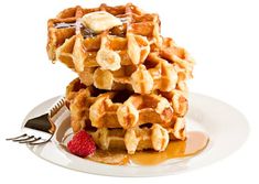 a stack of waffles on a plate with syrup drizzled over them