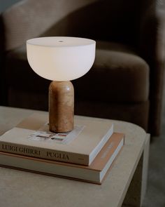 a table lamp sitting on top of a book next to a brown chair in a living room