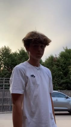 a young man standing in front of a parking lot