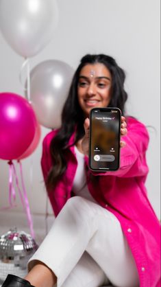 a woman sitting on the floor holding up her cell phone