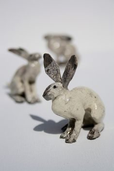 three small metal rabbits on a white surface