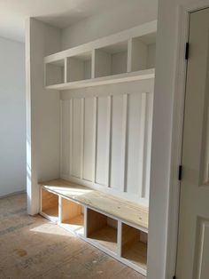 an empty room with some white shelves and wood flooring on the side of it