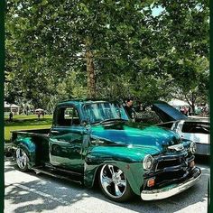 an old green truck parked in a parking lot