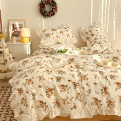 a bed with white comforter and pillows in a room next to a christmas tree