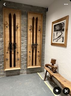 two wooden doors with skis on them in front of a stone wall and bench