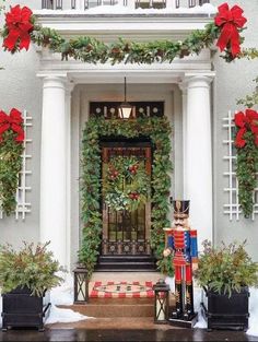 christmas decorations on the front door of a house with wreaths and poinsettias