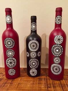 three wine bottles with designs on them sitting on a wooden table next to each other