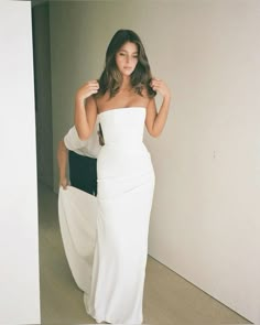 a woman in a white dress is posing for the camera