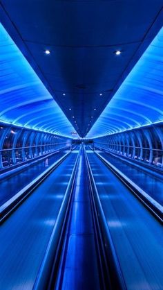 the inside of a subway station with blue lights on it's walls and floor