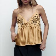 Add A Touch Of Elegance To Your Wardrobe With This Beautiful Zara Gold Camisole. The Sleeveless Top Features A Flattering V-Neckline And Strappy Sleeves, Making It Perfect For Any Occasion. The Embroidered Accents Add A Unique Touch To The Design, While The Lightweight Polyester Material Makes It Suitable For All Seasons. This Camisole Is Perfect For Travel, Parties, Casual Outings, Workwear, And Business Meetings. It Comes In A Size Xs And Is A Regular Fit. The Gold Color And Metal Theme Make I Sleeveless Top With Delicate Straps For Party, Sleeveless Party Top With Delicate Straps, Elegant Gold Camisole For Spring, Party V-neck Top With Delicate Straps, Spring Night Out Tops With Delicate Straps, Spring Tops With Delicate Straps For Night Out, Elegant Gold Tank Top For Summer, Delicate Strap Tops For Spring Parties, Spring Party Tops With Delicate Straps