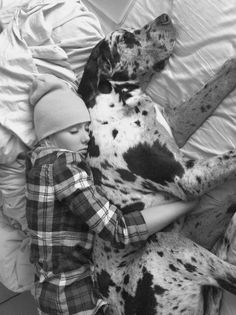 a black and white photo of a boy laying in bed next to a dalmatian