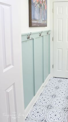 a painting hangs on the wall next to a white door and blue tile flooring