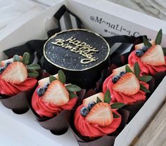 a box filled with cupcakes covered in frosting and topped with strawberries