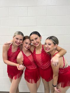 four women in red dresses posing for the camera with their arms around each other and pointing