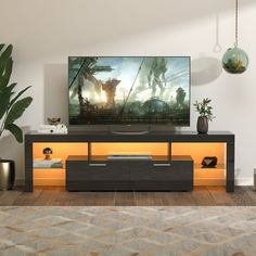 a flat screen tv sitting on top of a wooden entertainment center next to a potted plant