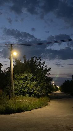 a street light on the side of a road at night with clouds in the sky