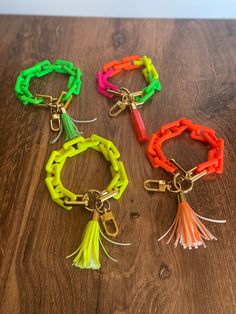 three different colored bracelets with tassels on top of a wooden table next to each other