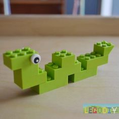 a green lego toy with an eye on it's head and eyes in the shape of a crocodile