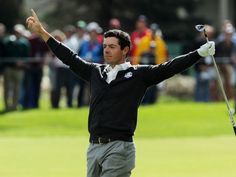 a man holding his arms up in the air while standing on top of a green