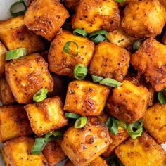 a white plate topped with fried tofu and green onion garnished with scallions