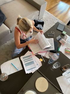 a woman is sitting at a table with papers and other things on the coffee table