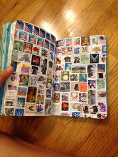 a person holding an open book with many stamps on it and the pages are covered in pictures