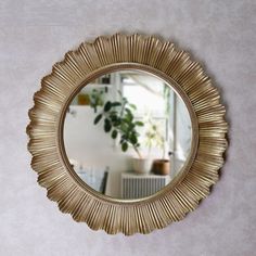 a mirror that is on the wall in front of a potted plant and table