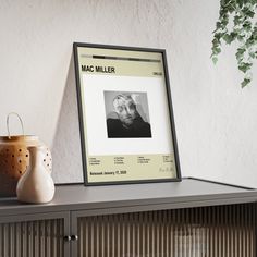 there is a framed photograph on top of a shelf next to a vase and potted plant