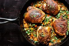 some meats and vegetables are cooking in a skillet