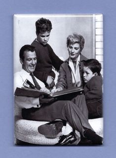 an old black and white photo of three people sitting on a couch with a young boy