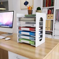 an office desk with a computer monitor, keyboard and file folders stacked on top of each other