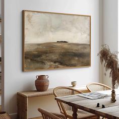 a painting hanging on the wall above a dining room table with chairs and a vase