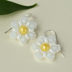 Our pearl flower earrings feature a cheerful, yellow pearl surrounded by over 150 white beads hand-woven into an intricate flower pattern.  The beaded flower dangles from sterling silver filled earrings that add a touch of sparkle.  The nature inspired jewelry will effortlessly enhance your style and add a pop of color to your summer wardrobe.  Embrace the beauty of nature with our lightweight, handmade earrings.  FIT:  The beaded flower is ¾ of an inch in diameter and the drop is roughly 1 inch Handmade Flower Pearl Earrings, Handmade Flower-shaped Pearl Earrings, Handmade White Pearl Earrings For Gift, White Sterling Silver Dangle Flower Earrings, Elegant White Flower Shaped Beaded Earrings, Summer White Pearl Drop Jewelry, Handmade Pearl Dangle Flower Earrings, Handmade Pearl Flower Jewelry, Delicate Handmade Flower Earrings For Summer