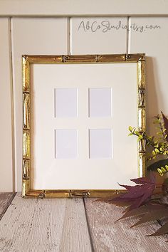 a white and gold frame sitting on top of a wooden table next to a potted plant