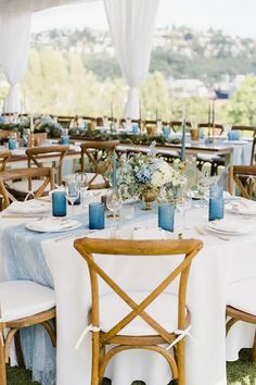 the tables are set with white linens and blue centerpieces for an outdoor wedding reception