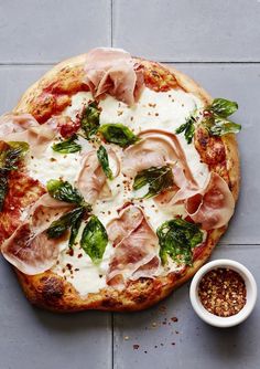 a pizza sitting on top of a pan covered in toppings next to a small bowl