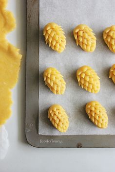 some yellow pastries sitting on top of a cookie sheet