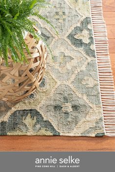 a potted plant sitting on top of a wooden table next to a blue and white rug