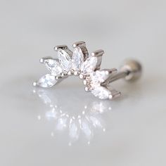 an image of a diamond ring on a white surface with the reflection of it's petals