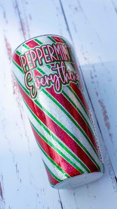 a can of peppermint candy canes on a white wooden table with red and green stripes